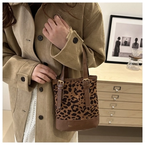 Close-up of leopard print bucket bag with leather handles and metallic buckle details