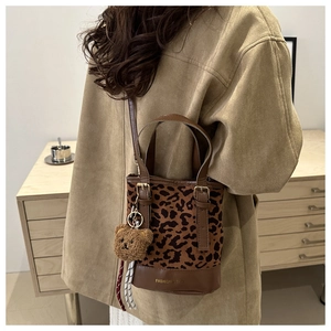 Detail of leopard print bucket bag with brown leather base and cute plush bear charm