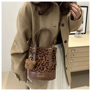 Detail of leopard print bucket bag with adjustable strap and cute teddy bear charm