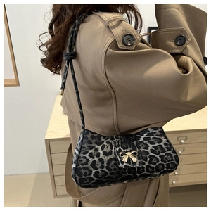 Detail der Schultertasche mit Leopardenmuster und goldener Schleife am Trenchcoat