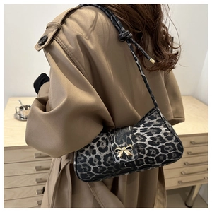 Detail der Leoparden-Schultertasche mit goldener Schleifenschnalle auf einem Trenchcoat