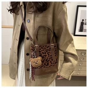 Detail of leopard print mini bucket bag with bear charm and adjustable leather strap