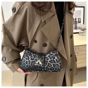 Detailed view of leopard print shoulder bag with elegant golden bow-knot buckle on trench coat