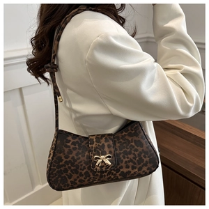 Detail der Schultertasche mit Leopardenmuster und goldener Schleife auf weißem Blazer
