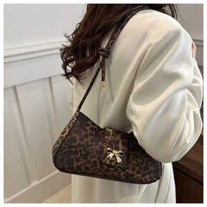 Close-up of leopard print underarm bag featuring a gold bow buckle and knotted strap