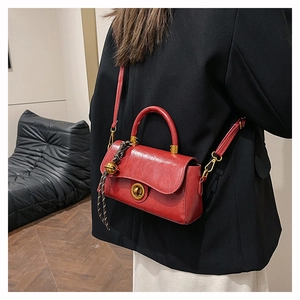 Détail du sac en cuir brillant rouge avec fermoir doré et charme en corde tressée
