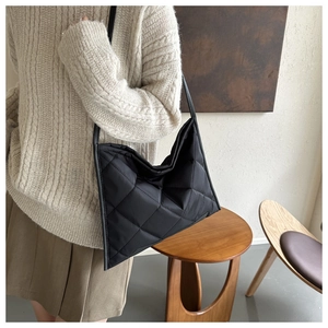 Detail of black quilted shoulder bag with diamond stitching on soft nylon fabric