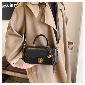 Détail du sac bandoulière vintage noir avec fermoir doré et charm cloche rayé