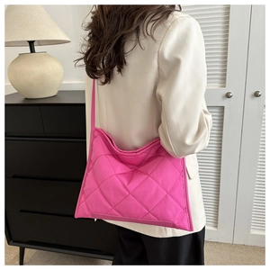 Detailed back view of a fuchsia quilted nylon tote bag worn by a model in a modern home