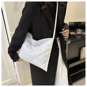 Modern white quilted tote bag worn with black suit for a stylish minimalist commuter look