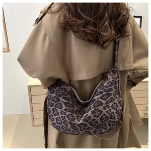 Detail of a large leopard print tote bag styled with a khaki trench coat for an autumn look