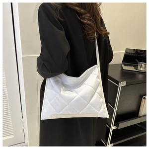 Detailed shot of white quilted tote bag with large diamond stitching and leather base