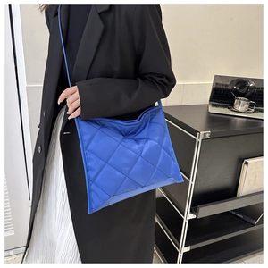 Close-up of bright blue quilted nylon crossbody bag with diamond stitching pattern