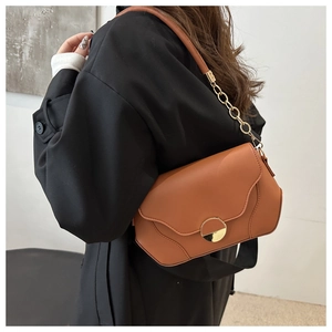 Detail of caramel brown PU leather crossbody bag with wave edge and gold metal buckle