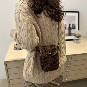 Mini sac bandoulière léopard rétro porté par un mannequin dans un décor vintage chaud