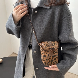 Sac bandoulière léopard avec garniture en cuir porté sur un manteau gris foncé