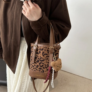 Chic leopard print bucket bag with brown leather trim and cute plush bear accessory