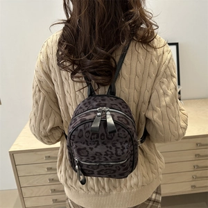Mini sac à dos imprimé léopard gris porté par un mannequin en pull en maille beige