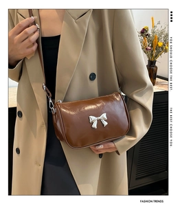 Détail d'un sac bandoulière en cuir PU marron avec boucle de nœud argenté sur blazer beige