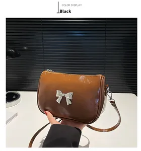 Gros plan sur le sac en cuir verni caramel avec ornement nœud argenté et accessoires