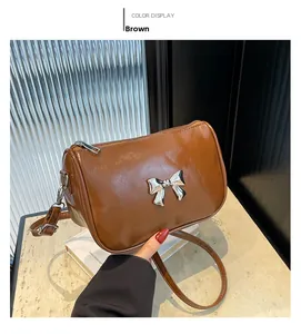 Détail d'un sac bandoulière marron en similicuir avec un nœud en métal argenté