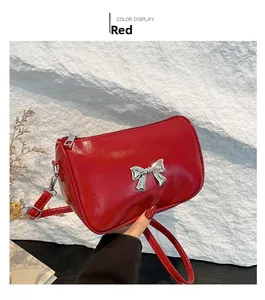 Détail du sac à bandoulière rouge brillant avec boucle nœud argentée et zip