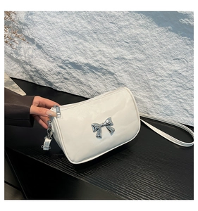 Détail du sac à bandoulière blanc avec nœud en métal argenté et fermeture éclair