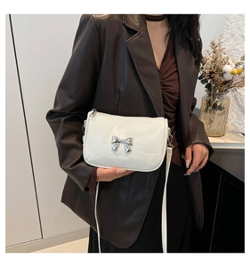 Sac bandoulière blanc tendance avec nœud argenté présenté sur un mannequin