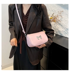 Détail du sac bandoulière rose clair avec nœud en métal argenté et bandoulière réglable