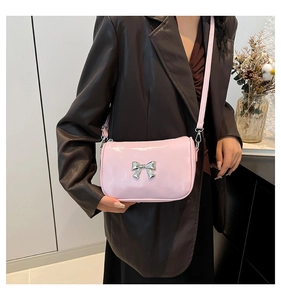 Détail du petit sac à main rose brillant avec noud argenté et bandoulière fine élégante