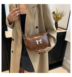 Détail d'un sac à bandoulière en cuir verni marron avec boucle en nœud argenté