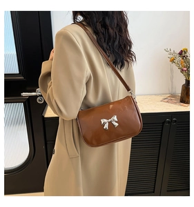 Sac bandoulière en similicuir marron avec nœud argenté porté par un mannequin pour la taille