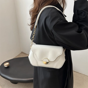 Minimalist white leather crossbody bag with gold buckle on a black coat model