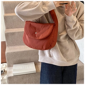 Detail of rust red quilted puffer bag showing the plush texture and silver snap button