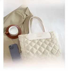 Detail of cream quilted tote bag with diamond pattern and fashion metal lettering