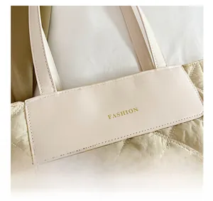 Detail of cream quilted nylon tote bag featuring a gold FASHION logo and diamond patterns