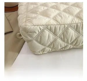 Close-up of precise quilting stitches and textured beige fabric on the tote bag bottom
