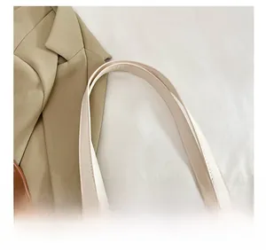 Detailed view of the comfortable flat shoulder straps on a beige quilted tote bag