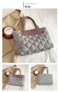 Detail of gray quilted tote bag featuring brown leather handles and fashion logo patch