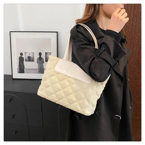 Detail of cream quilted tote bag featuring a diamond pattern and a smooth fashion flap