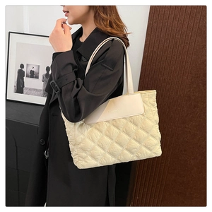Close-up of cream quilted down tote bag with leather strap and FASHION logo detail