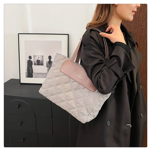 Detail of quilted tote bag with pink leather handles and gold fashion lettering logo