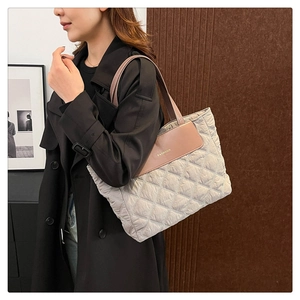 Detail of grey quilted nylon tote bag with brown leather strap and golden logo