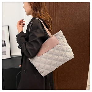Close-up of gray quilted tote bag with FASHION logo and pink-brown leather trim detail