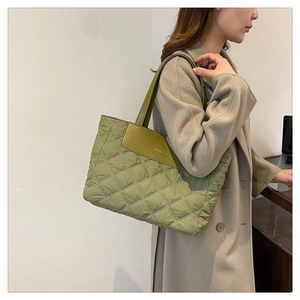 Detail of light green quilted tote bag featuring a leather patch with Fashion text