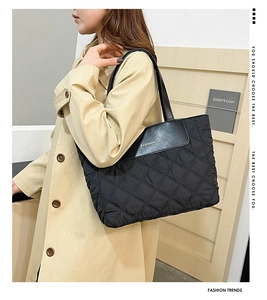 Detail of black quilted nylon tote bag with golden FASHION logo and faux leather trim