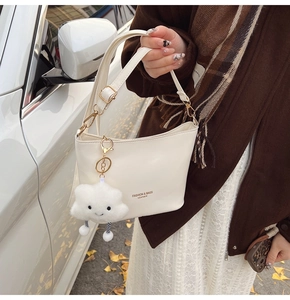 Detail of cream white bucket bag with leather texture and plush cloud charm accessory