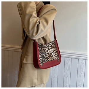 Detail of red leather shoulder bag with leopard print panel worn with a khaki blazer