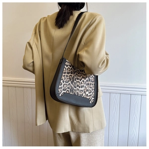 Close-up of leopard print shoulder bag with black leather trim worn by a model