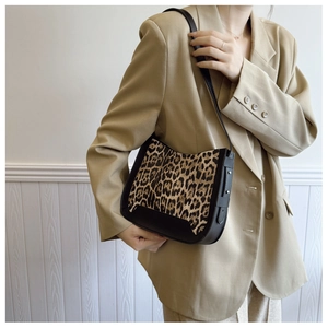 Detail of leopard print tote bag with black leather base shown on model in khaki blazer